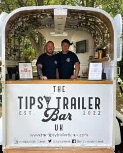 Two men standing behind the bar of a mobile bar called