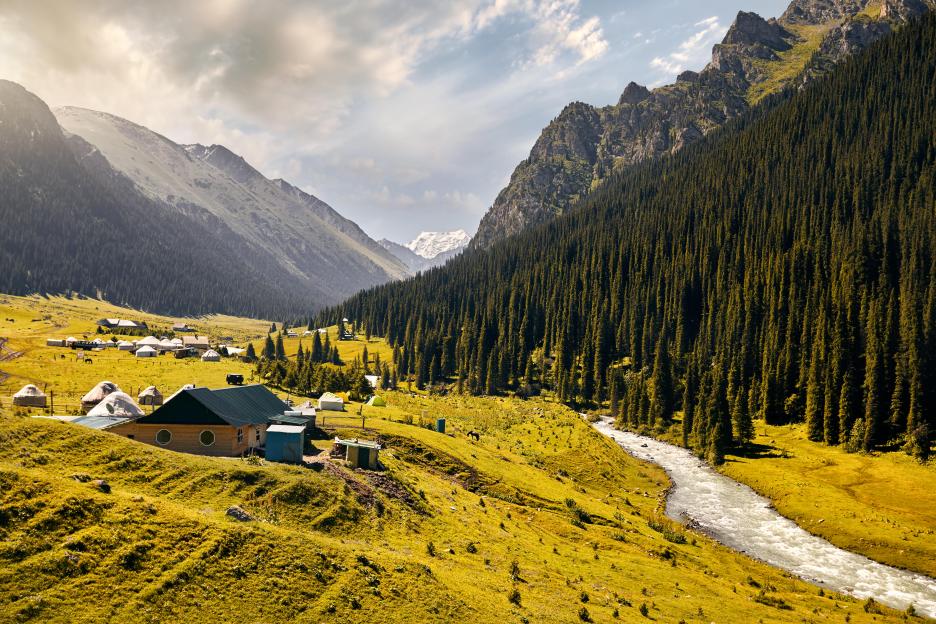 Arashan river and guest houses with yurts in the mountain valley of Altyn Arashan gorge, Kyrgyzstan.