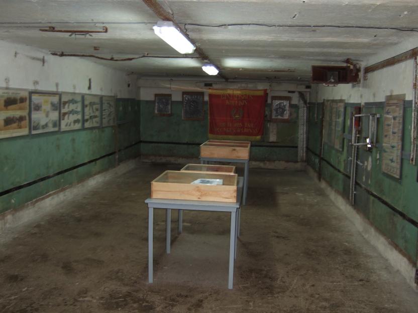 Interior of an abandoned Soviet-era nuclear missile base in Lithuania, showing display cases and informational posters.