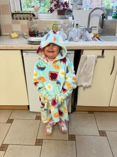 Girl in breakfast-themed hooded robe in kitchen.