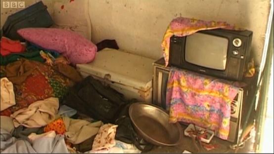 Interior of Osama bin Laden's compound in Abbottabad, Pakistan, showing a cluttered room with a television, clothes, and other belongings.