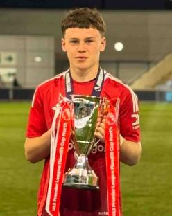 A boy holding a Premier League U15 Floodlit Cup North winners trophy.