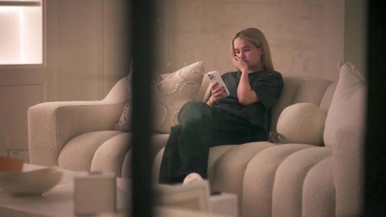Molly-Mae on a sofa looking at her phone.