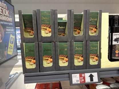 Several boxes of J.D. Gross Dubai Style chocolate bars on a store shelf.