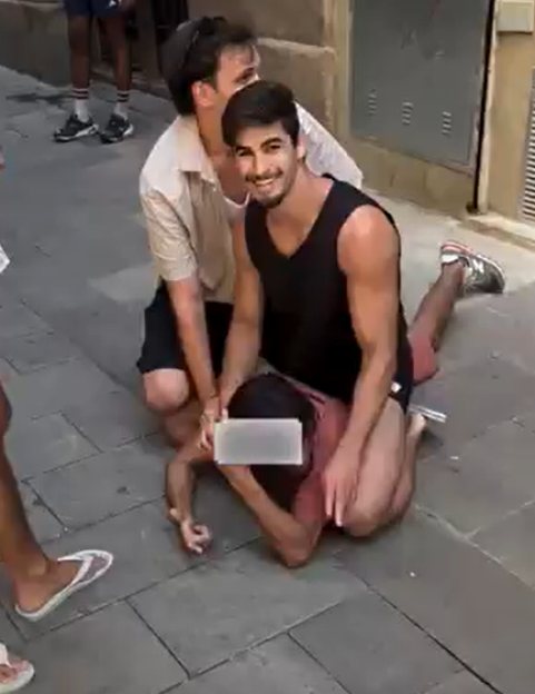 Two men holding down a person on the ground.