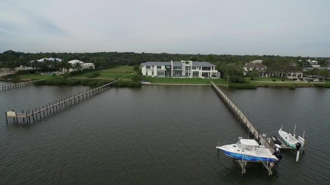 Rickie Fowler's Jupiter Island mansion from across the water, with a boat on a lift in the foreground.