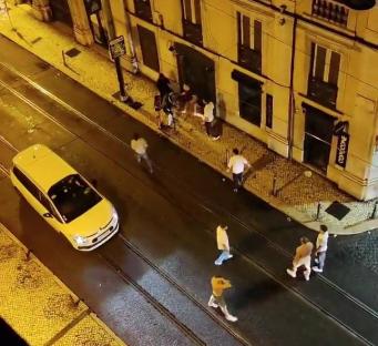 Nighttime street scene showing a group of people near a building, a yellow car, and a stabbing incident.