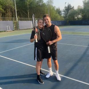 Two people holding tennis rackets on a tennis court.