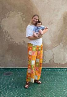 Woman holding a baby in front of a textured wall.