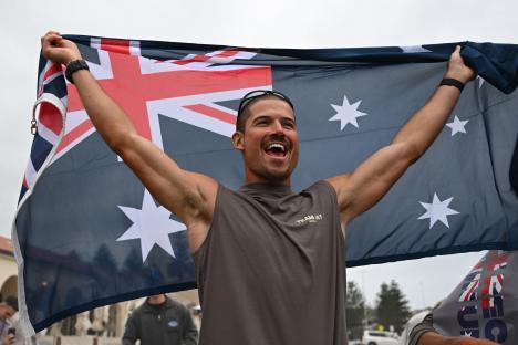 A runner holding an Australian flag after setting a new world record for the fastest run across Australia.