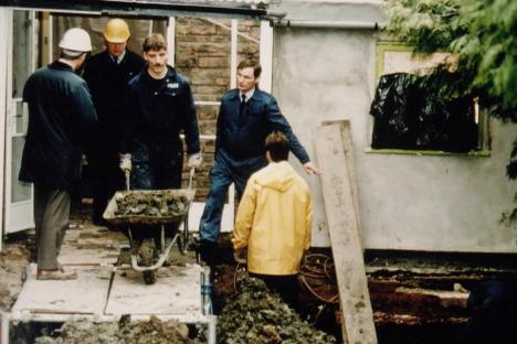 Police officers searching for human remains in a garden.