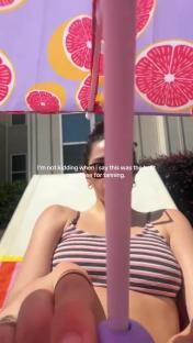 Woman sunbathing under a grapefruit-patterned umbrella.