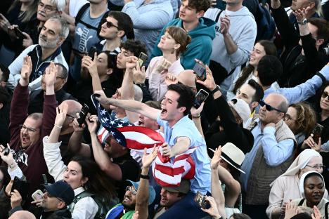 A crowd of people cheering, holding up an American flag, reacting to the announcement of a new pope.