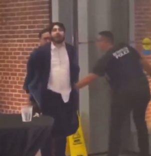 A man in a suit being detained by security.
