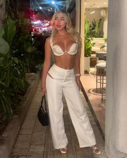 Woman in white outfit standing outside at night.