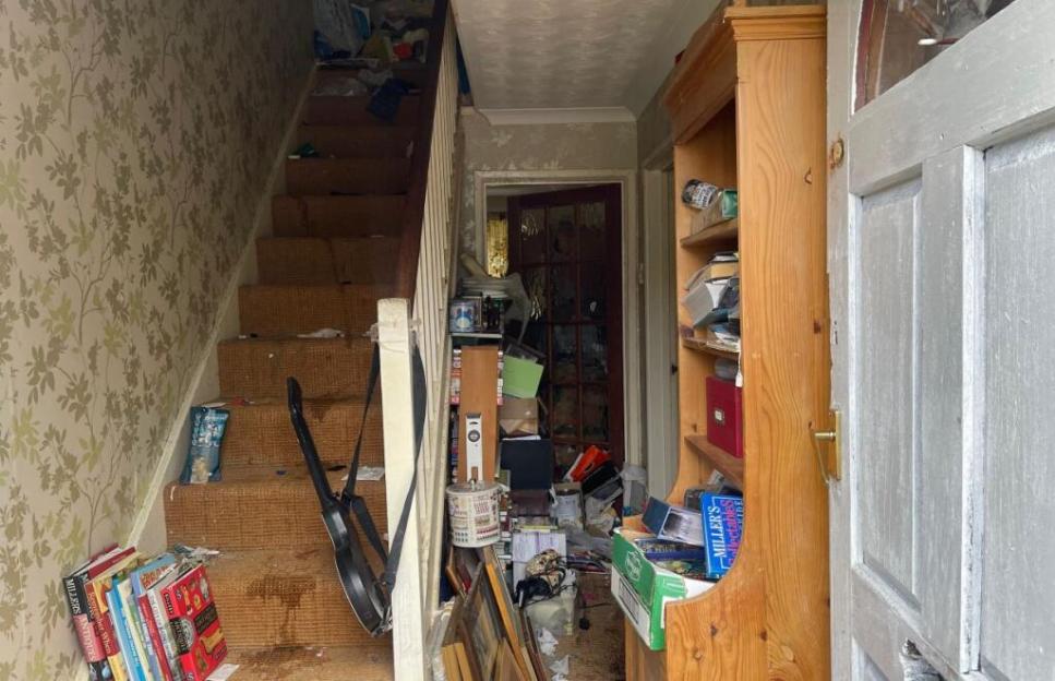 Messy hallway and staircase of a house for sale.