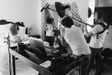 Black and white photo of a film crew filming a pregnant woman in a hotel room.