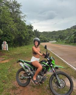 Young woman sitting on a green motorcycle in Thailand.