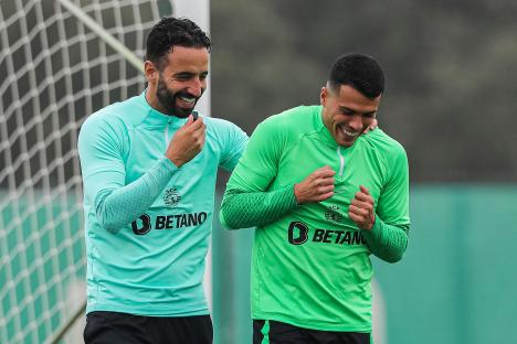 Two Sporting Lisbon soccer players laughing during training.