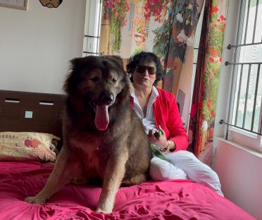 Man sitting on a bed with a large dog.