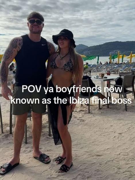Photo of a couple on a beach; the man has a distinctive bowl-cut hairstyle.