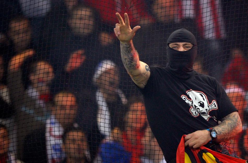 Serbian soccer fan wearing a balaclava and making a gesture.
