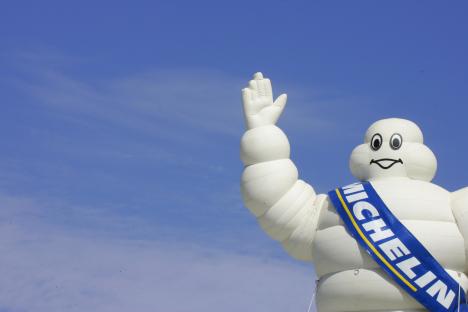Michelin Man inflatable waving against a blue sky.