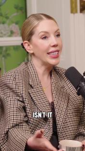 Woman in houndstooth jacket speaking into microphone.