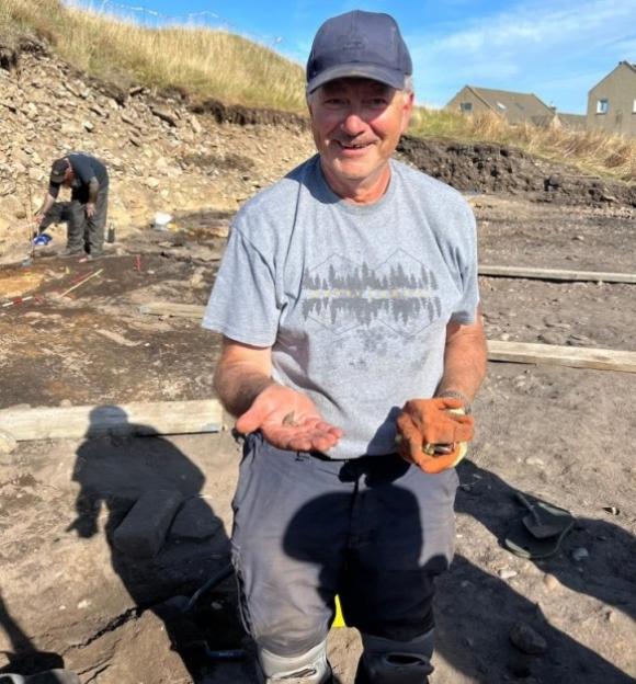 Volunteer holding a 1,000-year-old Pictish ring at an archaeological dig.