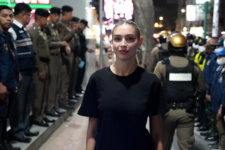 Woman standing before Bangkok police officers before a drug raid.