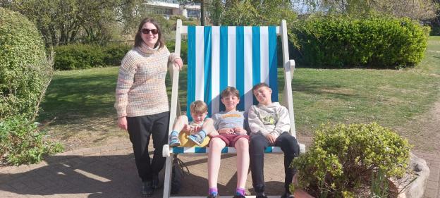 A woman and three children sitting in a large deck chair.