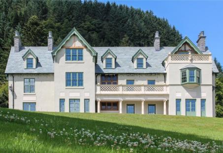 a large white house with green trim sits on top of a grassy hill