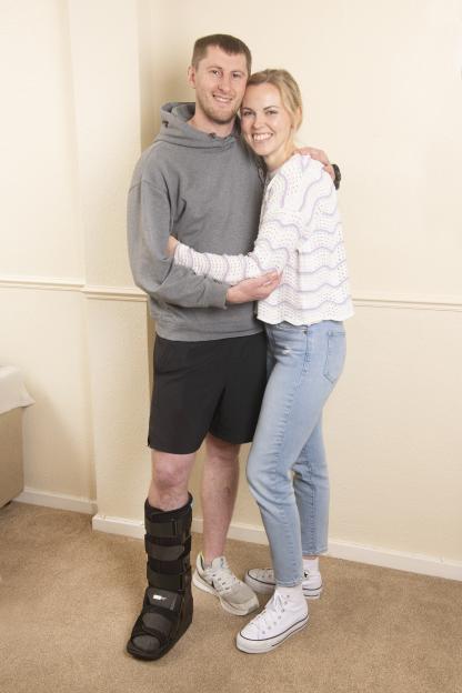 Newlyweds embracing, the groom wearing a leg brace.