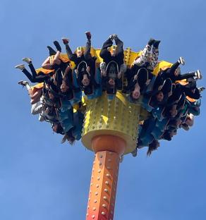 People upside down on a tall amusement park ride.