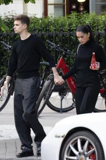 A young couple holding hands while walking past parked bicycles.
