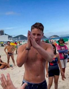 Man on a beach clapping his hands.