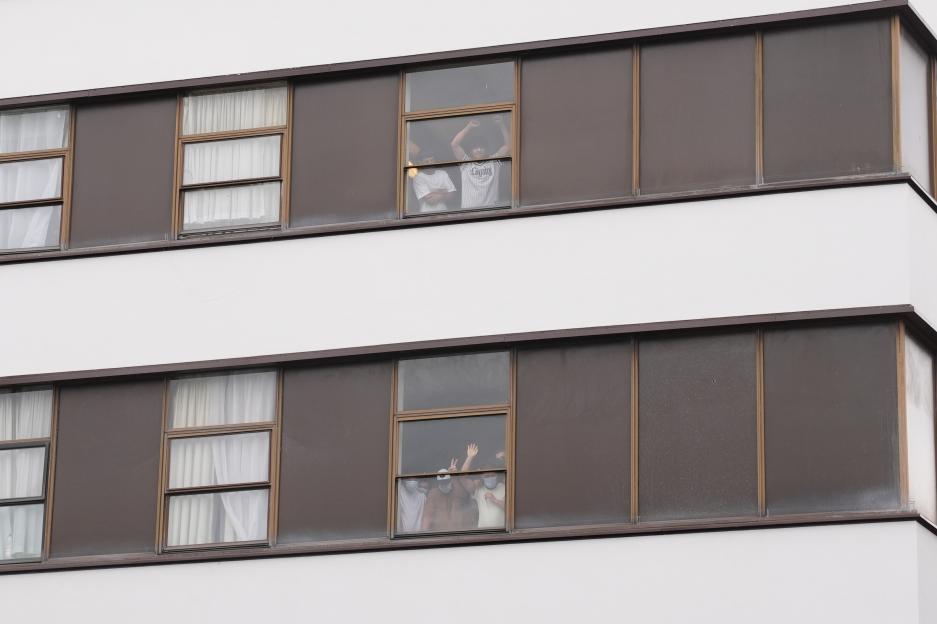 Hotel residents look out windows as protesters gather outside.