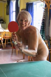 A nude woman playing table tennis.