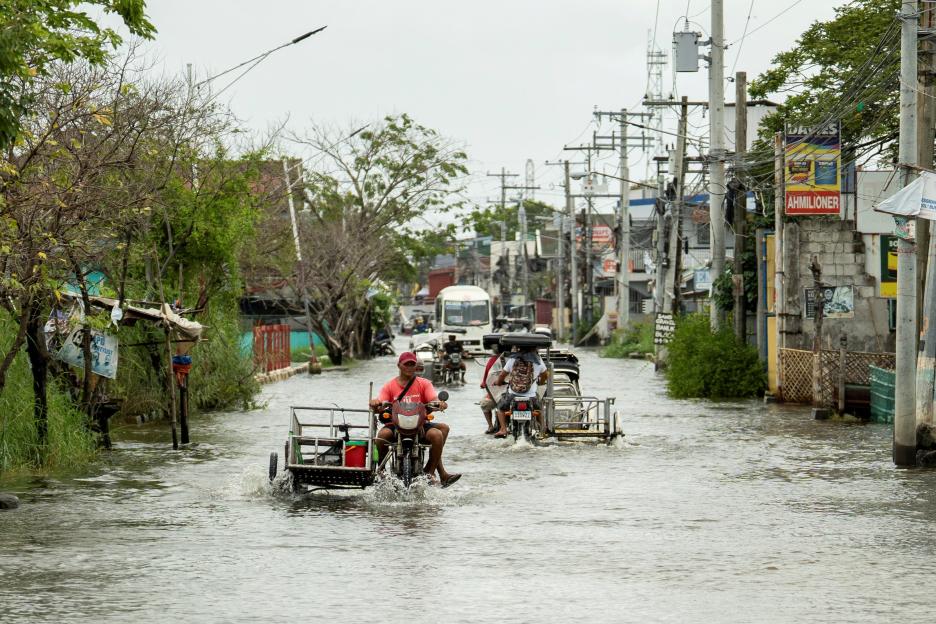 Motorists on tricycles and motorcycles wade through a flooded road in Apalit, Pampanga province, Philippines, following heavy rains intensified by Super Typhoon Ragasa.
