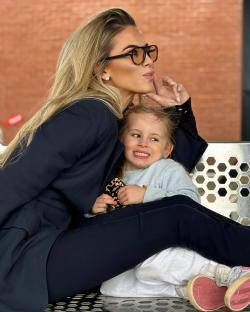 Woman in a black blazer sitting on a bench with a young child.