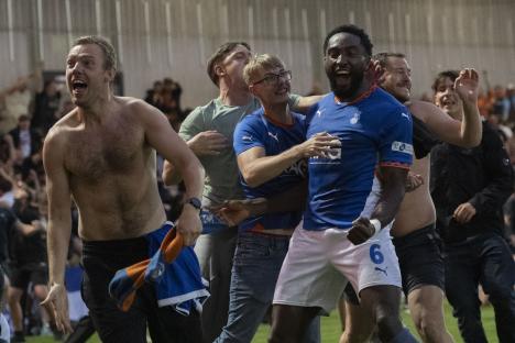 Emmanuel Monthe celebrates a goal with fans on the pitch.