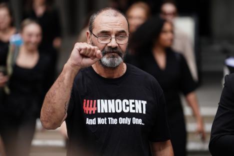 Andrew Malkinson, exonerated after 17 years in prison for a rape he did not commit, raises his fist. His shirt reads