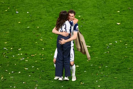 Ben Davies of Tottenham Hotspur celebrates with a woman on the field after a soccer game.