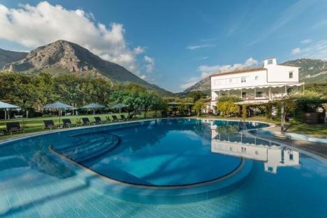 Hotel pool and building with mountain view.