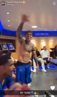Shirtless soccer player celebrating with teammates in locker room.