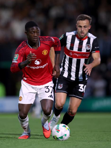 Manchester United's Kobbie Mainoo and Grimsby Town's Charles Vernam vying for the ball.