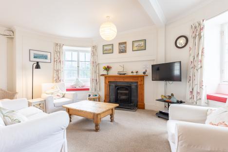 Living room with white sofas, fireplace, and TV.