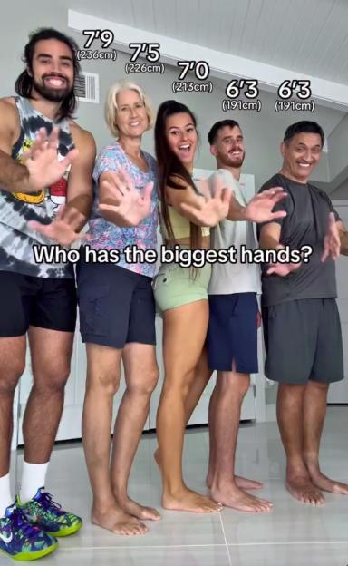 A tall family stands in a row, holding their hands out, asking "Who has the biggest hands?".