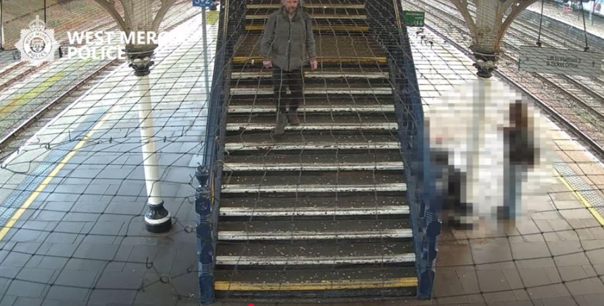 Surveillance image of a man walking down stairs at a train station.