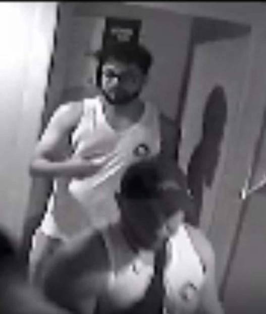 Black and white security camera image of a man grabbing a woman.